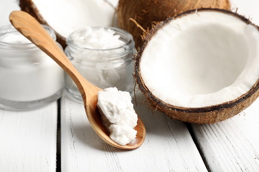 Coconut with jars of coconut oil and cosmetic cream on wooden background