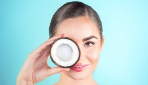 Beauty Woman with coconut Portrait. Spa model girl holding coco nut and smiling. Pretty young brunette woman face. Skin care. Youth. Beautiful Fashion Model Girl Face. Perfect Skin. Health care