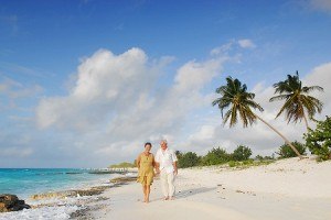 Senior couple walking on beach with coconut palm tree