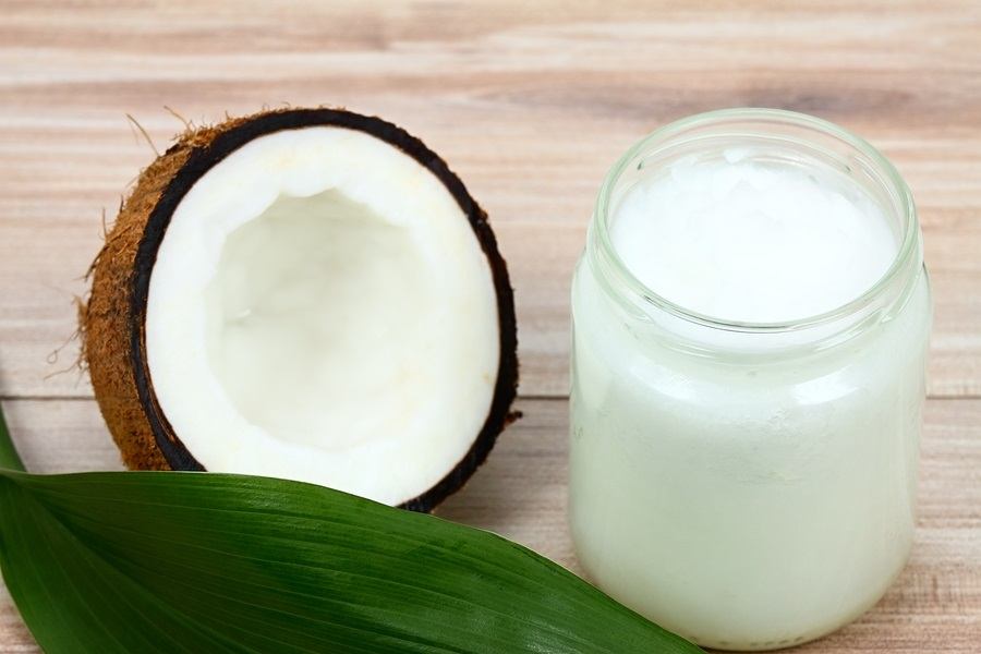 Organic coconut oil in the glass jar. Fresh coconut cut in half and leaf for decoration