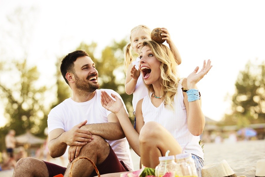 Happy family is enjoying beach and playing with coconut.