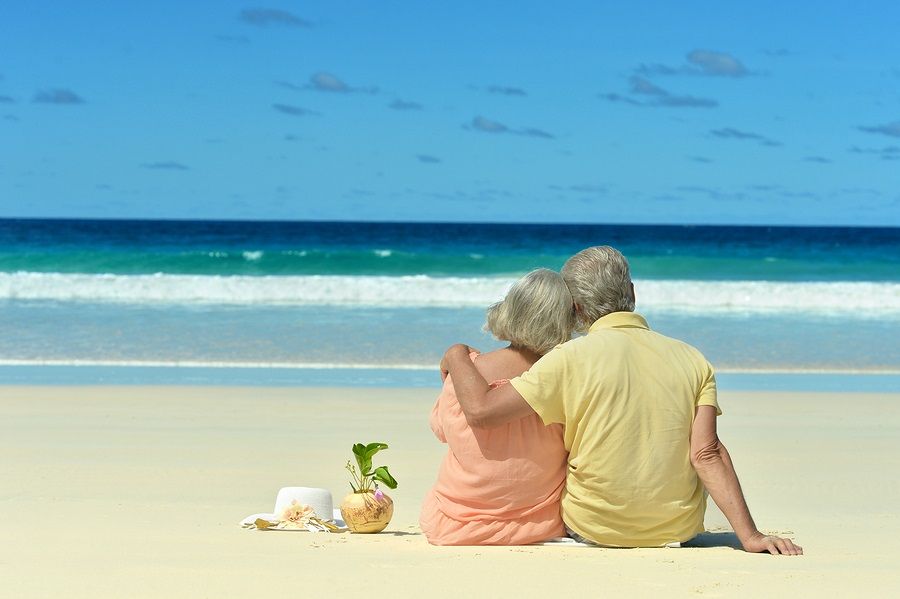 Couple sitting on the shore and looks at sea. 